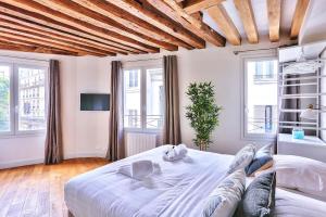 a bedroom with a large white bed with windows at St Michel - Deluxe Apartment - Harpe in Paris