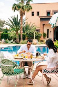 a man and woman sitting at a table by a pool at La Villa Des Golfs & PinkCactus in Marrakech