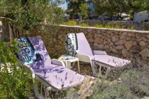 two purple chairs sitting next to a stone wall at La Casita Holiday Home in Petrcane