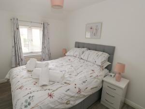 biała sypialnia z łóżkiem z białą pościelą i oknem w obiekcie 39 Mariners Quay w mieście Port Talbot