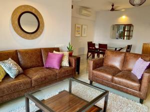 a living room with two brown couches and a mirror at Kanakia Paris D wing at BKC, Near Asian Heart Hospital, A Luxury Stay by Connekt Homes in Mumbai