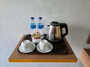 uma bandeja com comodidades para preparar café, chávenas e garrafas de água em Thyesza Hotel em Ambarita