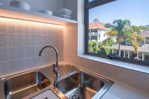 een keuken met een wastafel en een raam bij Brand New Seapoint Apartment in Kaapstad