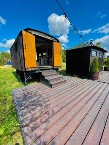 a tiny house sitting on top of a wooden deck at Wake nams ar pirtiņu in Jēkabpils +6 photos