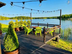 a wooden deck with a table and chairs on the water at Wake nams ar pirtiņu in Jēkabpils