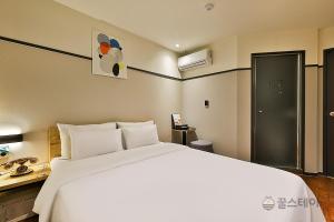 a bedroom with a large white bed and a bathroom at No25 Hotel Bupyeong in Incheon