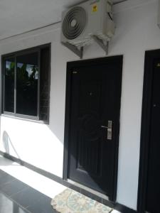 eine schwarze Tür mit einem Ventilator neben zwei Fenstern in der Unterkunft GreenSpring in Cape Coast