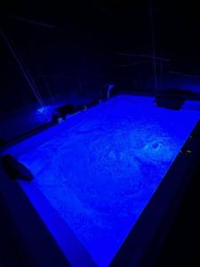 een zwembad met blauwe verlichting in een donkere kamer bij Black & White Luxury Rooms in Bari