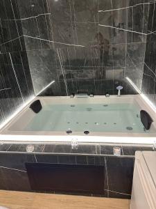 een badkamer met een bad en een betegelde muur bij Black & White Luxury Rooms in Bari