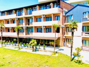 an apartment building with palm trees in front of it at Aparthotel costa in Makhinjauri