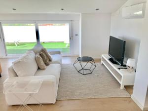 een woonkamer met een witte bank en een televisie bij La Pau Apartaments in Mollerusa