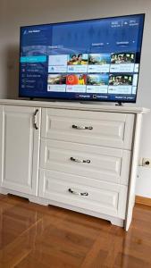 - une télévision au-dessus d'une commode blanche dans l'établissement Biser apartman, à Belgrade