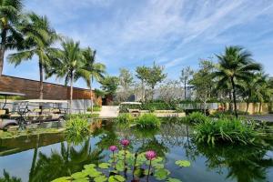 a garden with palm trees and a pond with flowers at Moon Villa Phu Quoc - 3 Bedroom - Private pool in Phú Quốc