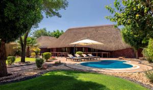 منتجع نوفا الرياض، راديسون كوليكشن في Ţibrāk: حديقه خلفيه فيها مسبح ومظله