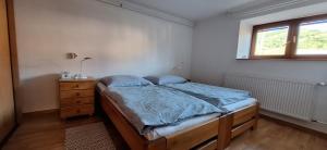 a bedroom with a bed and a dresser and a window at Apartmán Nelka pri Muránskej Planine in Muránska Dlhá Lúka