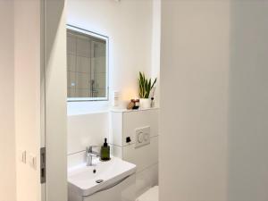a white bathroom with a sink and a mirror at MyStay - Zentral - Design - Prime - Küche in Heidelberg