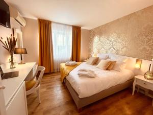 a bedroom with a bed and a desk and a window at Le Royal Picardie in Albert