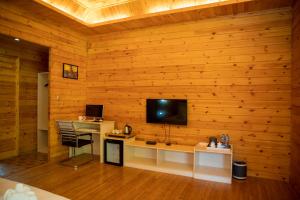 Pokój z telewizorem na drewnianej ścianie w obiekcie Butterfly Valley w mieście Ban Na Phoc Thap