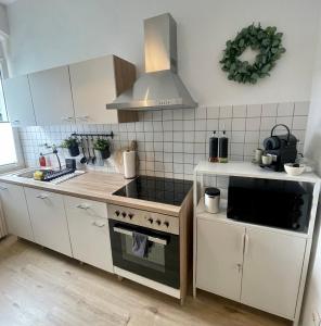een keuken met witte kasten en een fornuis met oven bij Perfekt für 5 - Stylisch & Zentral - Küche in Essen