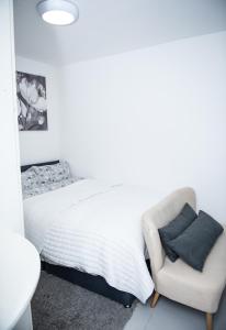 a white bedroom with a bed and a chair at 1B Apartment, 30 mins to Oxford Street in London