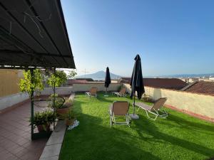 a patio with chairs and umbrellas on the grass at B&B Terrazza In Centro in Castellammare di Stabia