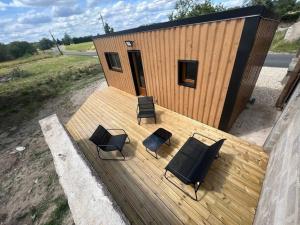 a deck with four chairs and a small building at Le Marronnier in Billy
