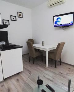 a white table with chairs and a tv on a wall at Apartmani Banja Vrujci Lux in Gornja Toplica