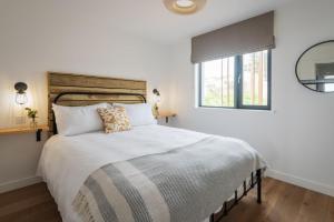 a white bedroom with a large bed and a window at Apartment 14, Withie Cove in Hope Cove