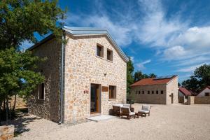 a brick house with two chairs and a building at Dionis Zaton - Camping, Glamping, Holiday Houses & Rooms in Zaton