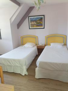 two beds in a room with white walls and wood floors at Les Géraniums Sullylois in Sully-sur-Loire