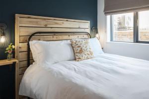 uma cama branca com uma cabeceira em madeira e uma janela em Apartment 7, Elender Cove em Hope-Cove