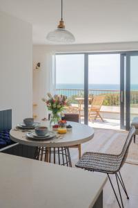 uma cozinha com mesa e cadeiras com vista para o oceano em Apartment 8, Forest Cove em Hope-Cove