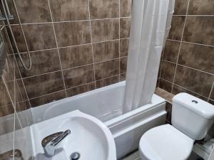 Impeccable 1-Bed Apartment in Ilford في إلفورد: حمام مع مرحاض ومغسلة وحوض استحمام