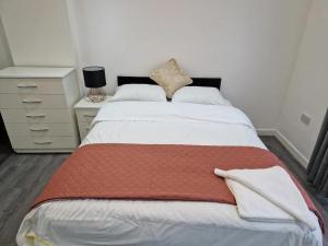 Impeccable 1-Bed Apartment in Ilford في إلفورد: غرفة نوم مع سرير مع بطانية حمراء عليه