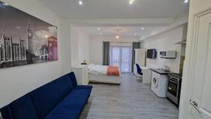 a living room with a blue couch and a bedroom at Impeccable 1-Bed Apartment in Ilford in Ilford