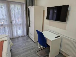 Impeccable 1-Bed Apartment in Ilford في إلفورد: غرفة مع مكتب وكرسي أزرق وتلفزيون