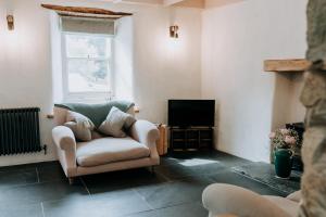 a living room with a chair and a television at Cute and cosy 2 bed cottage in beautiful Solva in Solva