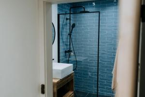 a bathroom with a sink and a shower with blue tiles at Cute and cosy 2 bed cottage in beautiful Solva in Solva