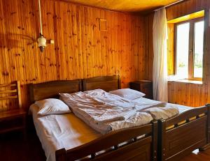 una camera con un letto su una parete in legno di Guesthouse Angelina a Ushguli