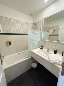 a bathroom with a sink and a tub and a mirror at Le Royal Picardie in Albert