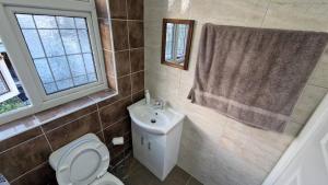 a bathroom with a toilet and a sink and a window at Captivating 2-Bed Apartment in Ilford in Ilford