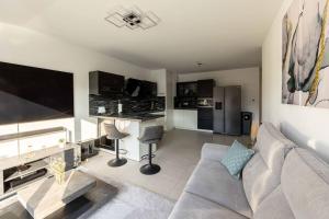ein Wohnzimmer mit einem grauen Sofa und einem TV in der Unterkunft Les Jardins d'Aix in Aix-les-Bains