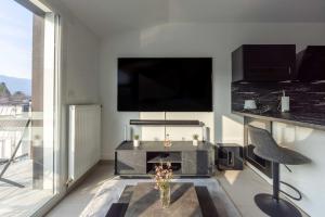uma sala de estar com televisão e uma mesa com lareira em Les Jardins d'Aix em Aix-les-Bains