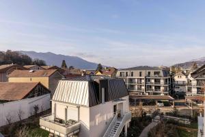 ein weißes Haus mit einem Metalldach in einer Stadt in der Unterkunft Les Jardins d'Aix in Aix-les-Bains