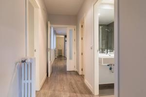 a hallway with a bathroom with a sink and a mirror at Castellana Suites in Madrid