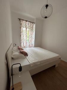 a bedroom with a white bed with a window at Nina & Lola in Rijeka