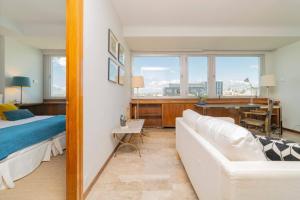 a living room with a couch and a bed and a desk at Colon Suites in Madrid