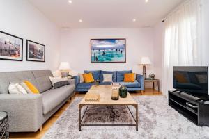 uma sala de estar com um sofá e uma televisão em Juan Bravo Suites em Madri