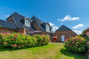 uma grande casa de tijolos com flores no quintal em Landhaus Nici em Westerland