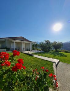 ein Haus mit roten Blumen im Hof in der Unterkunft Ornament: Infinite Nature Villa in Dhafnés